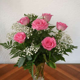 Pink roses arranged in a clear glass vase with white baby's breath