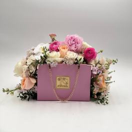 Pink and white flower arrangement in a lavender gift box with a chain handle