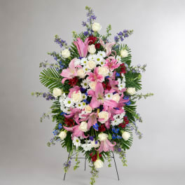 Standing floral spray with pink lilies, white roses, and daisies on an easel