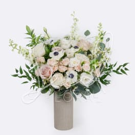 Bouquet of white and blush roses in a tall textured vase