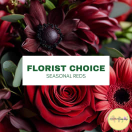 Red roses and dark burgundy flowers with a florist choice label