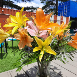 Bouquet of yellow, orange, and pink lilies in a glass vase