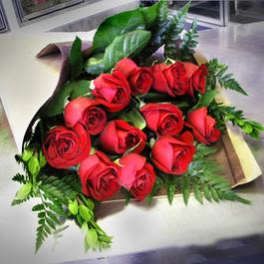 Bouquet of red roses with greenery wrapped in paper