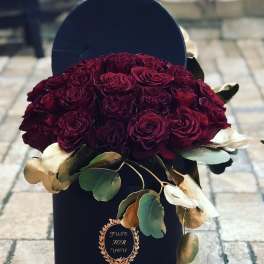 Bouquet of deep red roses in a black hatbox with eucalyptus