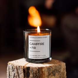 Lit candle in a glass jar on a wood stump