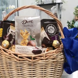 Wicker basket filled with assorted chocolates and a blue ribbon bow