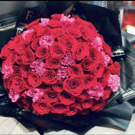 Large bouquet of red and pink roses wrapped in black paper