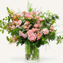 Large pink and green floral arrangement in a clear glass vase