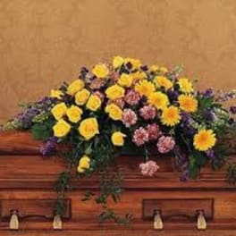 Yellow and pink floral arrangement on a wooden casket