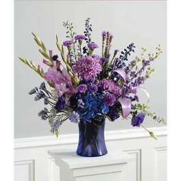 Purple and blue mixed flower arrangement in a dark blue vase
