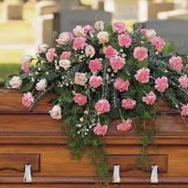 Pink and white carnations arranged on a wooden casket