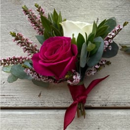Pink and white rose boutonniere with greenery and a ribbon tie