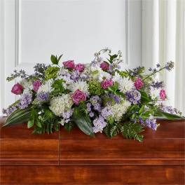Pink and white floral spray with purple accents on a casket