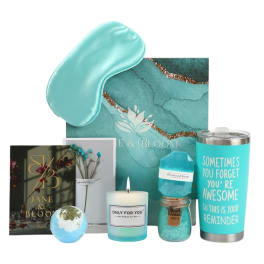 Teal self-care gift set with sleep mask, candle, tumbler, bath items, and cards