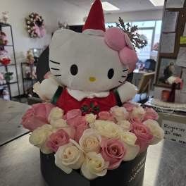 Hello Kitty plush in a red Santa hat surrounded by pink and white roses
