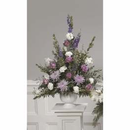 Tall floral arrangement in a white urn with purple and white blooms