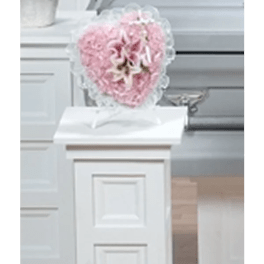 Pink floral heart arrangement on a white pedestal