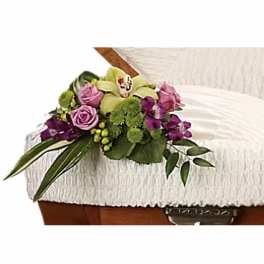 Purple and green floral spray on a white casket