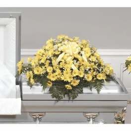 Yellow floral casket spray with a ribbon on a silver casket