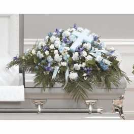 White and blue funeral casket spray with ribbon and cross