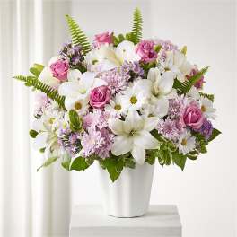 Pink roses and white lilies arranged in a white vase