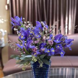 Purple iris bouquet in a blue glass vase