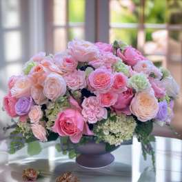 Pink and peach rose arrangement in a dark vase