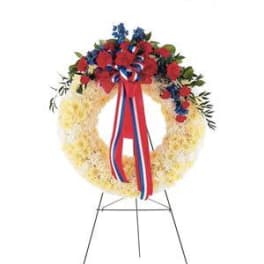 Red, white, and blue floral wreath on a metal stand with ribbon