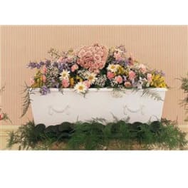 Large pastel floral arrangement in a white casket