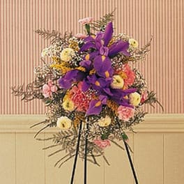 Standing floral spray with purple and pink flowers on a black easel