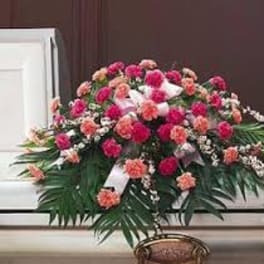 Pink and peach floral casket spray with white ribbon accents