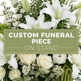 White lilies and roses arranged around a funeral sign on a stand