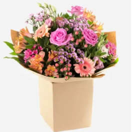 Mixed bouquet of pink and peach flowers in a beige box