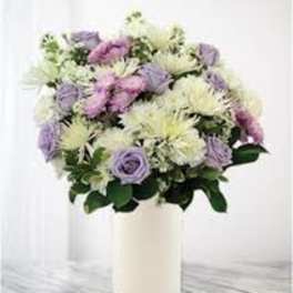 Lavender and white flowers arranged in a white vase