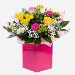 Mixed bouquet in a bright pink gift box with yellow, pink, white, and green flowers