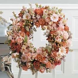 Large floral wreath of peach and blush roses on a stand
