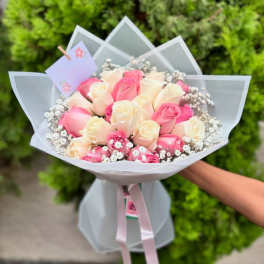 Bouquet of pink and cream roses wrapped in white paper