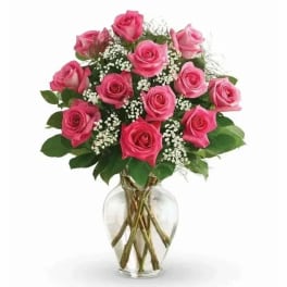 Pink roses arranged in a clear glass vase with baby's breath