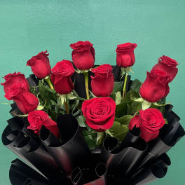 Bouquet of red roses wrapped in black paper with a red ribbon