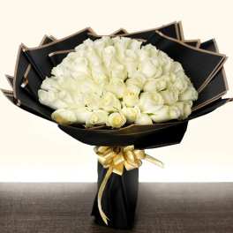 Bouquet of white roses wrapped in black paper with a gold ribbon