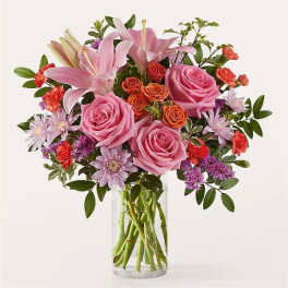 Pink roses and lilies arranged in a clear glass vase