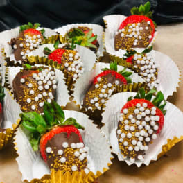 Chocolate-covered strawberries in paper cups with white and gold sprinkles