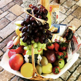 Fruit and snack basket with grapes, strawberries, apples, and packaged crackers