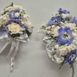 Two small wedding bouquets with blue and white flowers tied with white ribbon