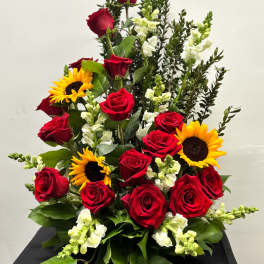 Tall arrangement of red roses, yellow sunflowers, and white snapdragons in a fan-shaped design