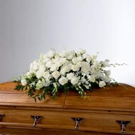 White rose casket spray on a wooden coffin