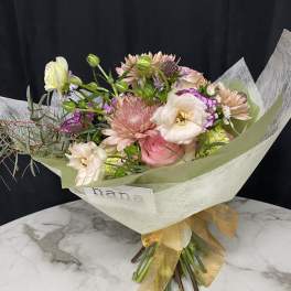Pastel bouquet with pink and white blooms wrapped in pale paper