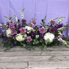 Low floral arrangement with lavender roses, white blooms, and purple accents