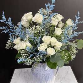 White roses in a blue-and-white ceramic vase with airy blue filler
