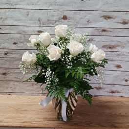 White roses arranged in a glass vase with baby's breath.